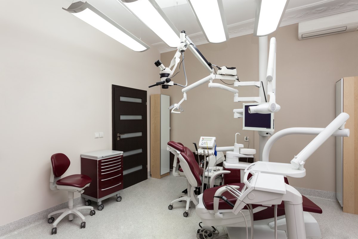Gabinete dental con sillón, lámpara y microscopio, preparado para recibir a un paciente