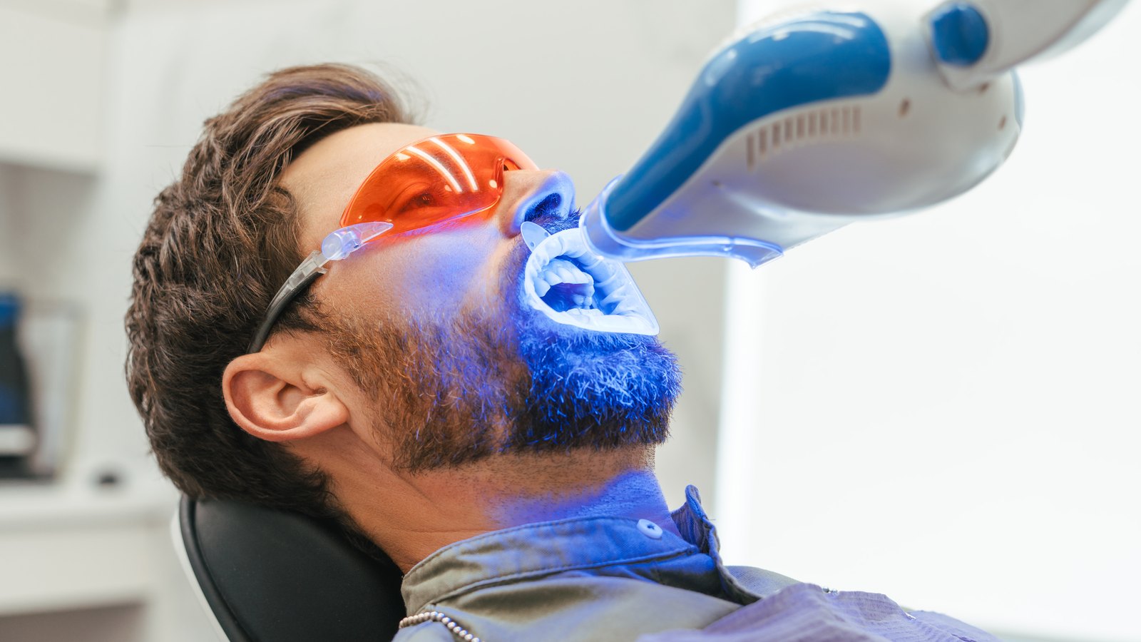 Paciente con gafas protectoras durante un blanqueamiento dental con lámpara