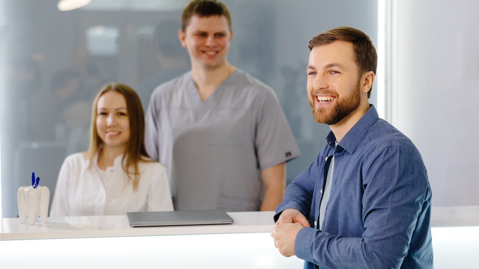 Paciente sonriente en la recepción de una clínica dental, con el equipo detrás