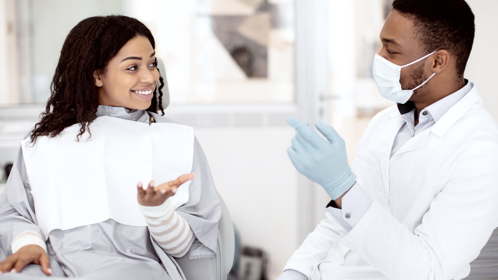 Odontólogo explicando el tratamiento a una paciente en el sillón dental