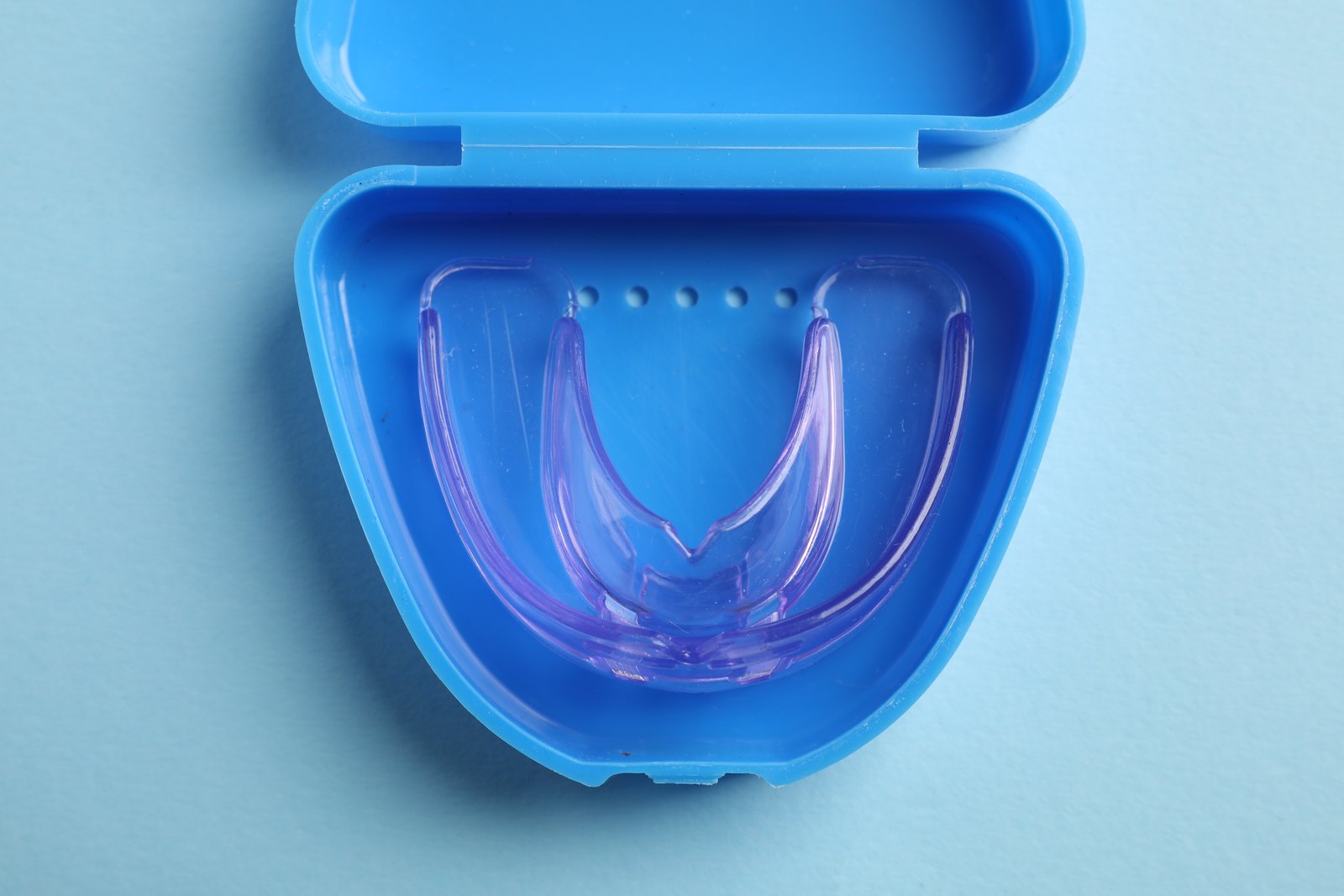 Férula dental transparente guardada en su estuche azul abierto